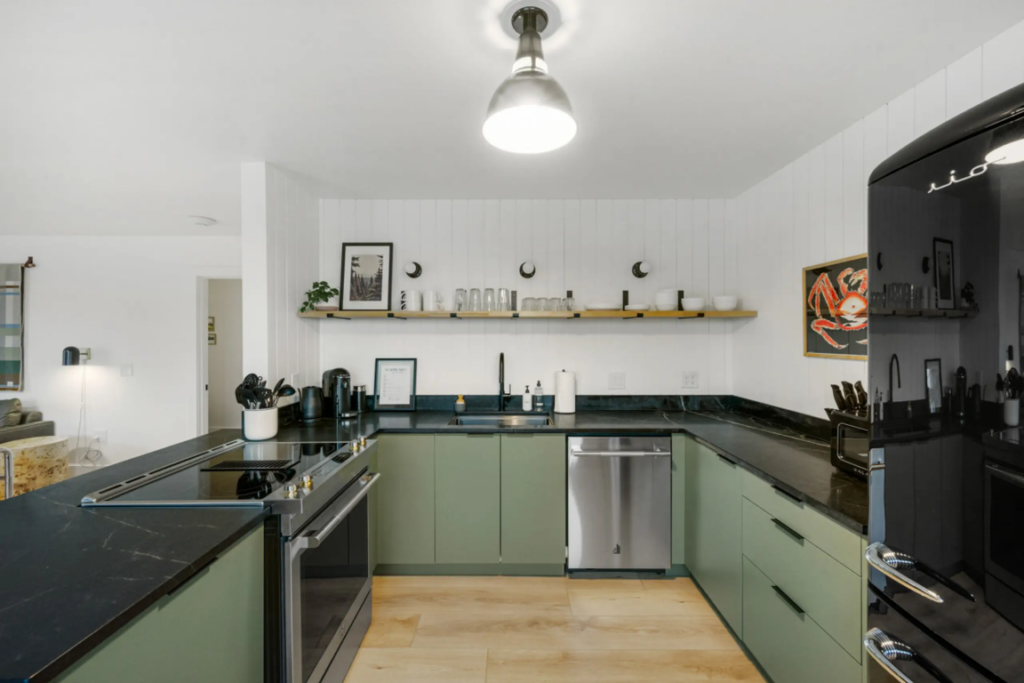 Modern kitchen with green cabinets and black countertops