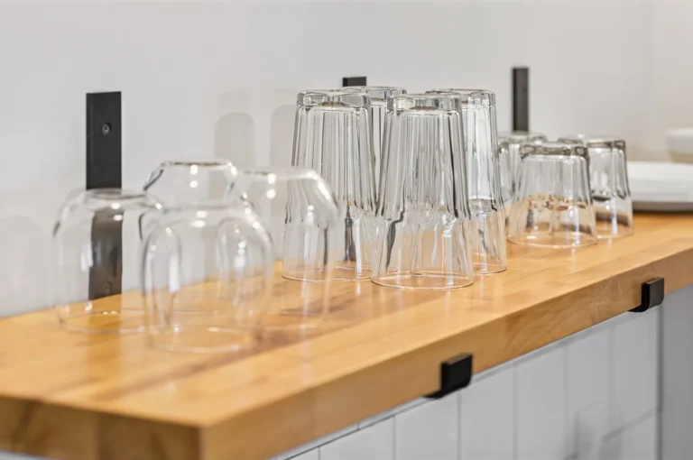 Clean glasses drying on wooden kitchen shelf