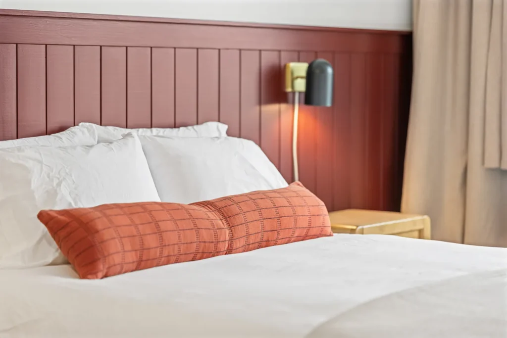 Cozy bed with red pillow and wall lamp