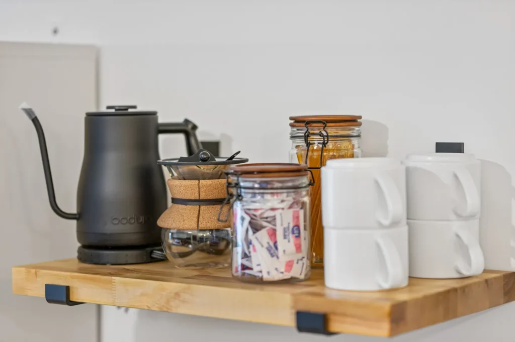 Coffee kettle, jars, and mugs on wooden shelf