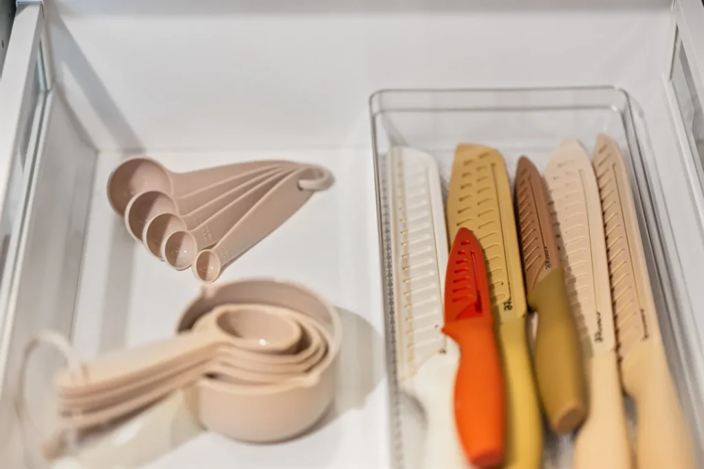 Measuring cups and kitchen knives in drawer organizer
