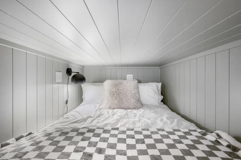 Cozy loft bed with white bedding and lamp