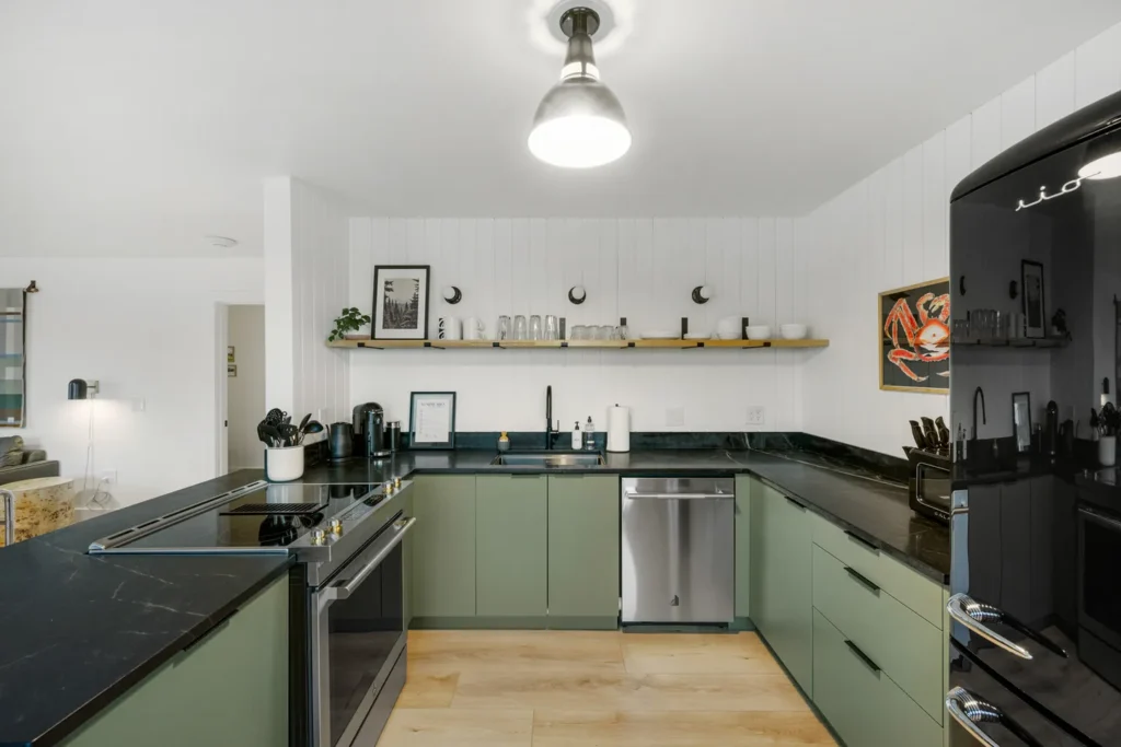 Modern kitchen with green cabinets and black countertops