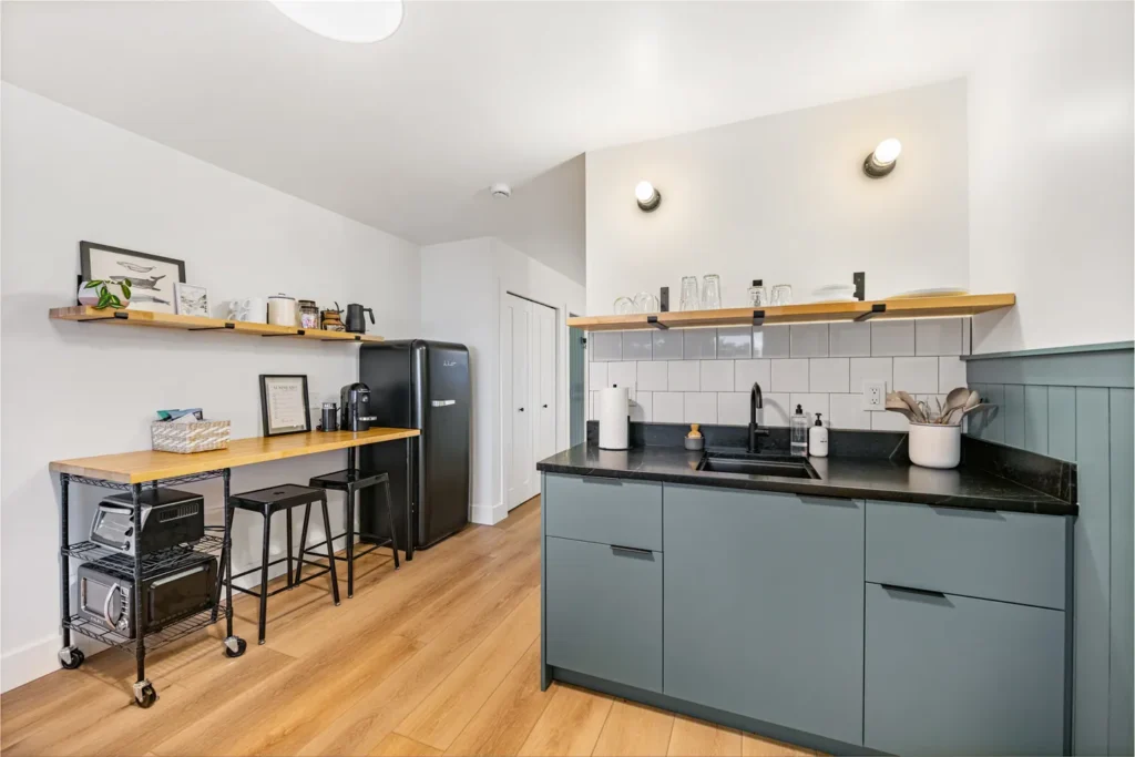 Modern kitchenette with black fridge and wood shelves