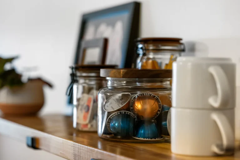 Coffee pods and mugs on wooden shelf