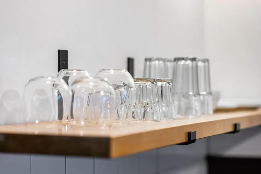 Clean glass cups drying on wooden shelf