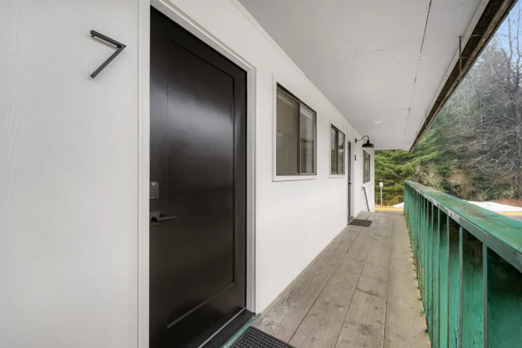 Outdoor hallway with black door and green railing