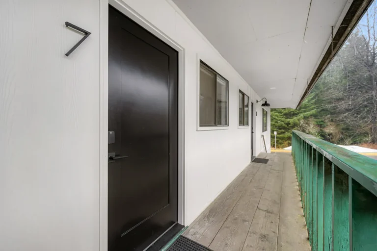 Outdoor hallway with black door and green railing