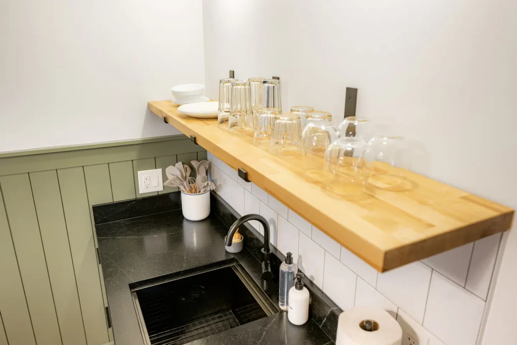 Modern kitchen sink with wooden shelf and glassware