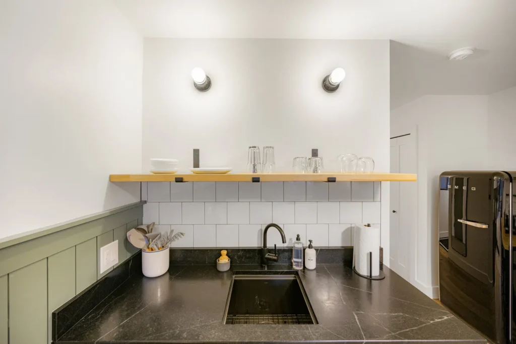 Modern kitchen sink with black countertop and fridge