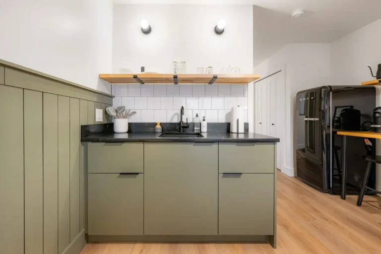Modern kitchen with green cabinets and black countertop