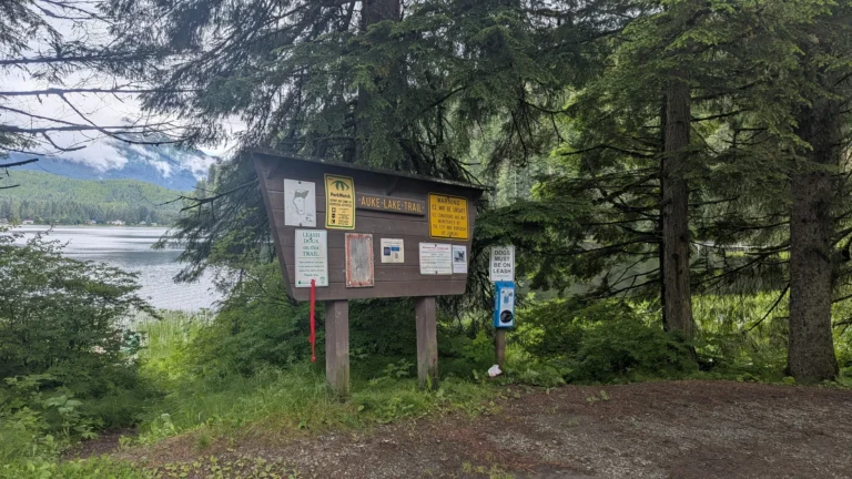 Auke Lake Trail sign surrounded by forest trees