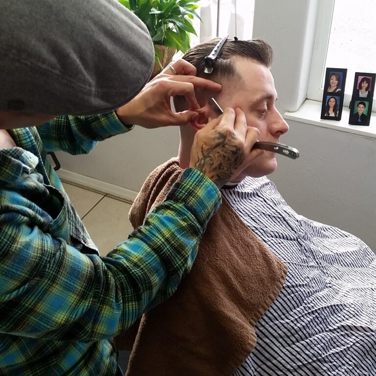 Barber giving man a haircut with razor