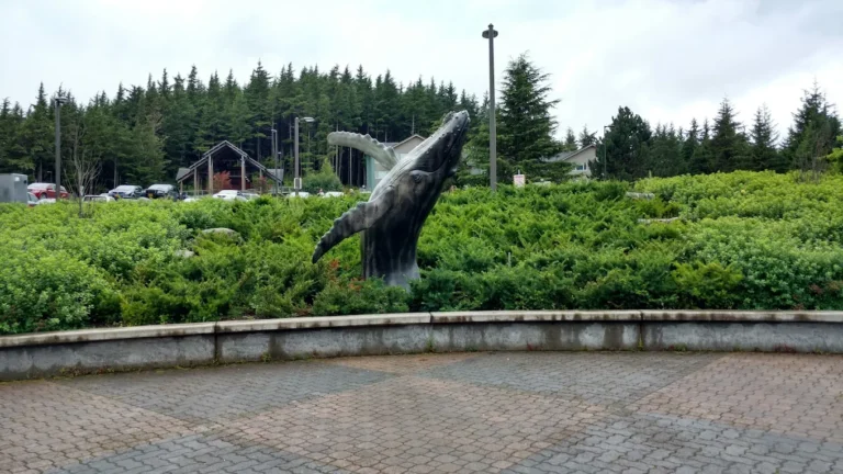Whale statue rising from greenery near forest park